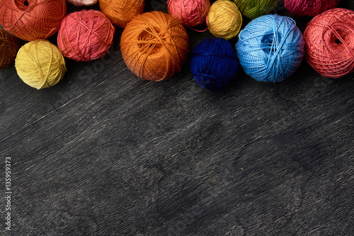 Colorful balls of yarn on wooden background of chalk board.