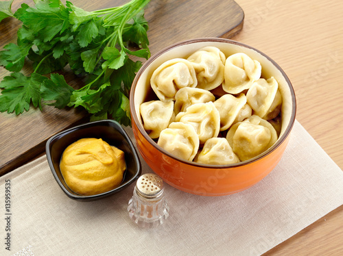 Russian dumplings - pelmeni, in orange bowl with mustard