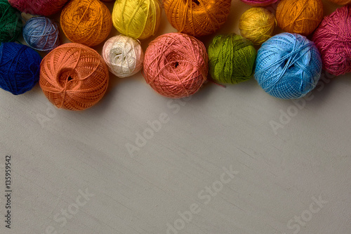 Colorful balls of yarn on white wooden background.