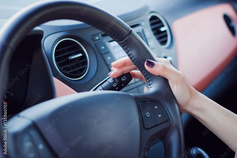Woman push the button on a steering wheel in car