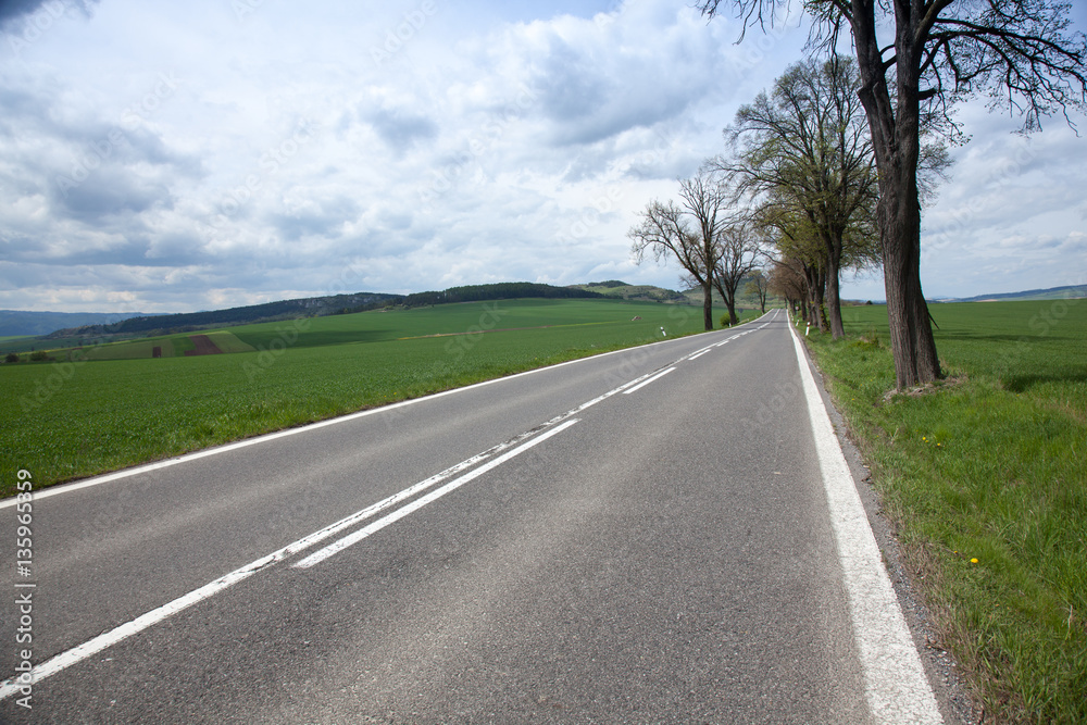 asphalt road through the green field and clouds on blue sky asphalt road through the green field and clouds on blue sky