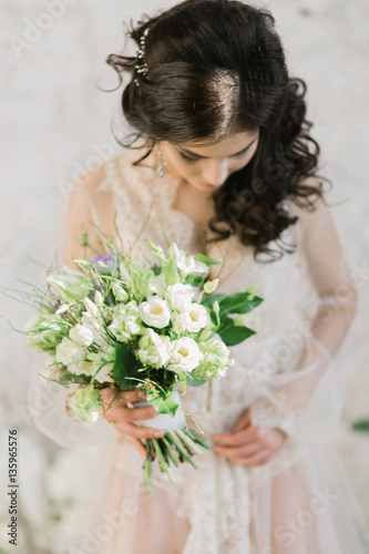 girl in boudoir dress looks at the bouquet