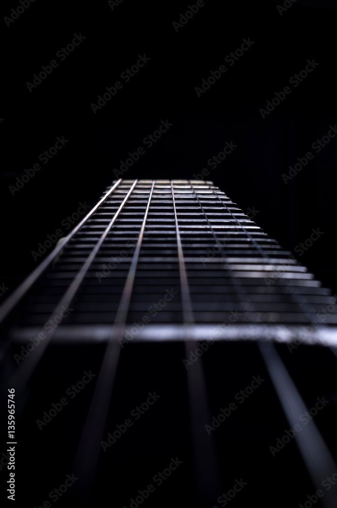 A guitar fretboard with strings on black background A guitar fretboard with strings on black background