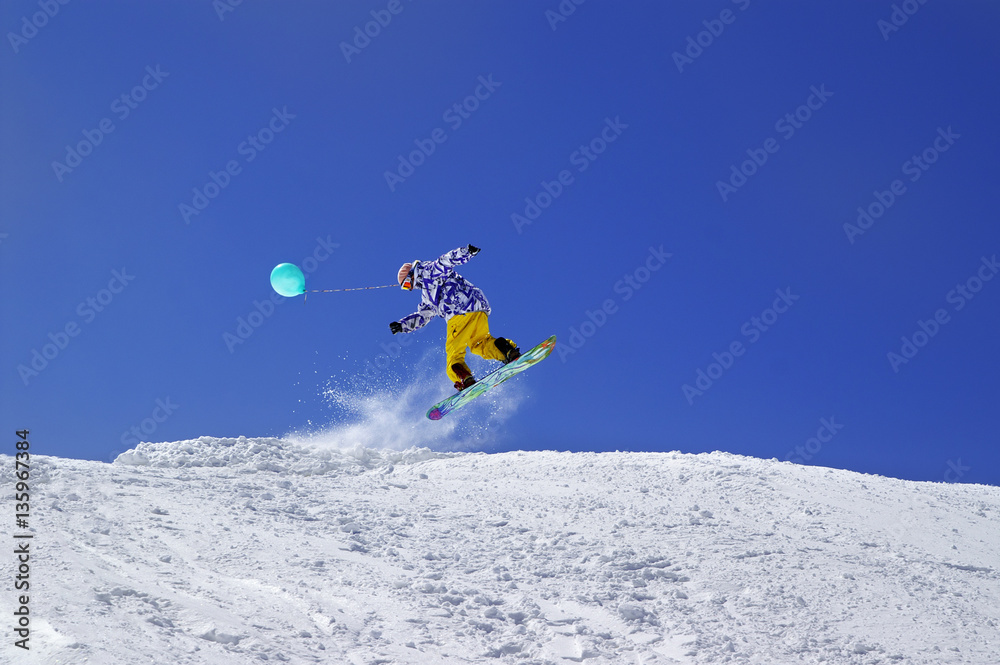 Snowboarder jump with toy balloon in terrain park at ski resort