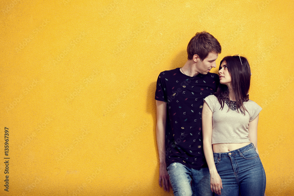 Couple posing in fashion style on yellow wall Couple posing in fashion style on yellow wall