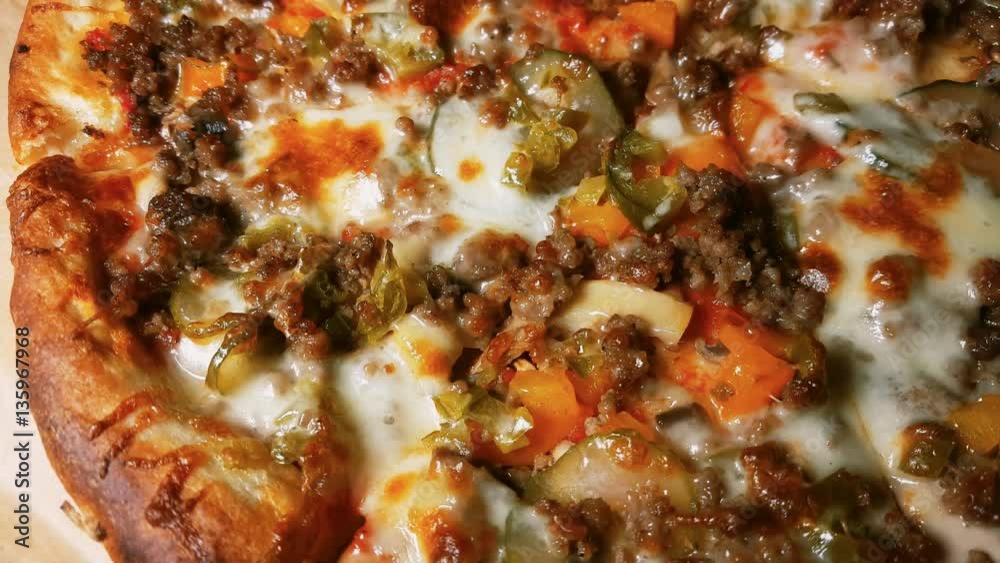 Hot pizza with meat, olives, cheese and vegetables rotate on table. Macro shot. Hot pizza with meat, olives, cheese and vegetables rotate on table. Macro shot.