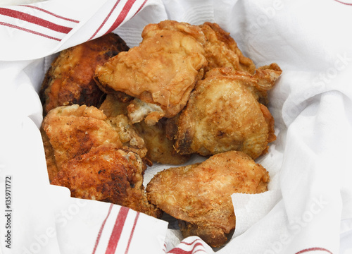 Homemade picnic fried chicken resting in cloth with red trim. photo