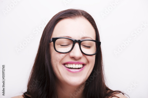 Happy young brunette woman wearing eyeglasses with eyes closed