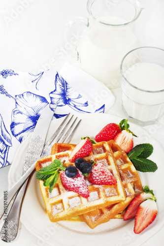 Hot homemade belgian waffles with berries and milk on light back