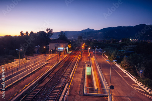 Perspective view of a elevated car road crossing a train track, in the background Apuan Alps, Versilia,Italy © jon11