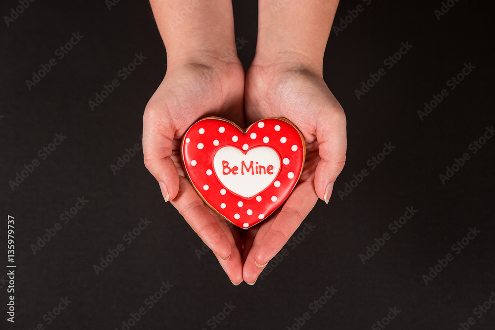 Beautiful gingerbread heart in the hands of the girl on a black background. Postcard for Valentine's Day, March 8, mother's Day or wedding. Free space for text Beautiful gingerbread heart in the hands of the girl on a black background. Postcard for Valentine's Day, March 8, mother's Day or wedding. Free space for text
