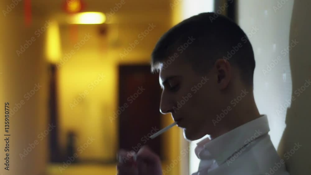 The man smokes and slowly exhales the smoke. Slow motion. Backlight