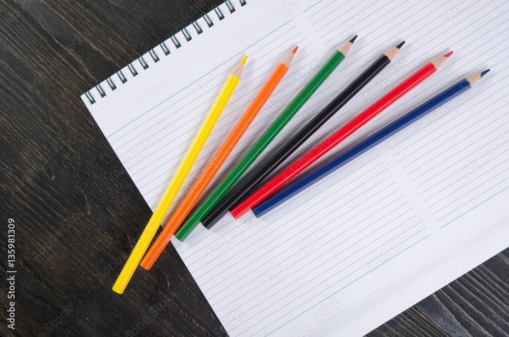 Colored pencils and a notebook Colored pencils and a notebook