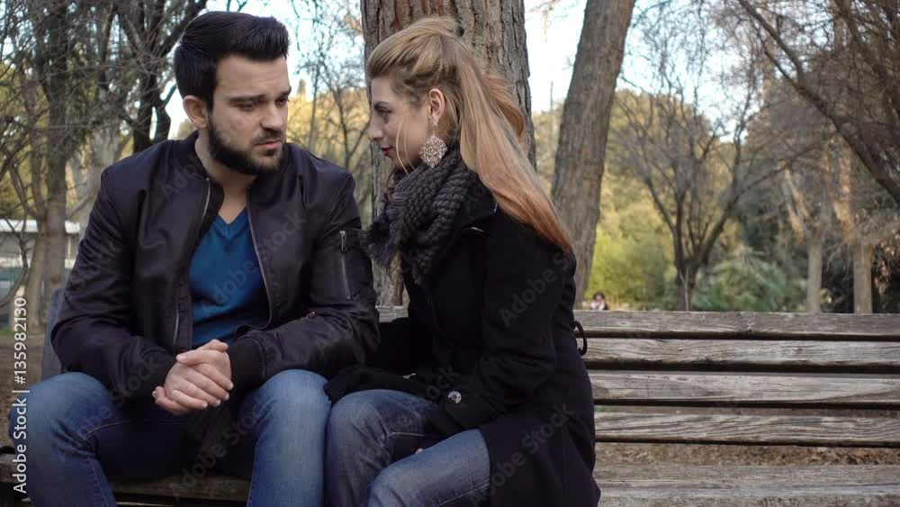 loving couple gently talk and cuddle on a bench at the park loving couple gently talk and cuddle on a bench at the park