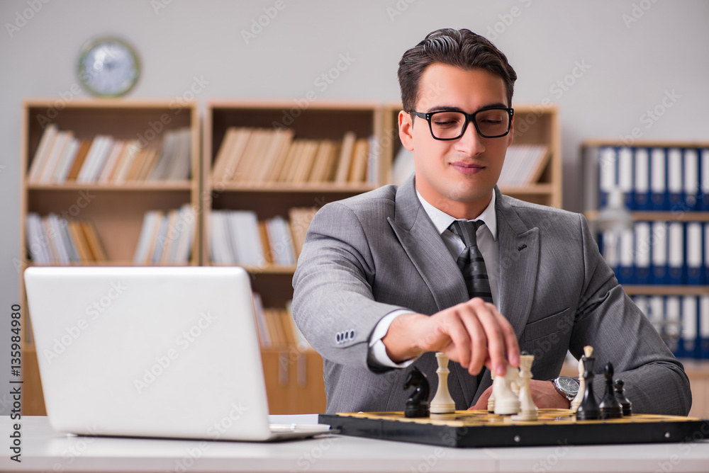 Young businessman playing chess in the office Young businessman playing chess in the office