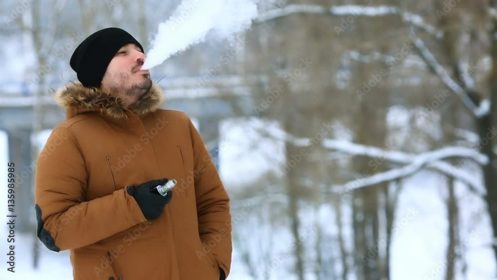 Man with beard smoke electronic cigarette outdoor. Man with beard smoke electronic cigarette outdoor.