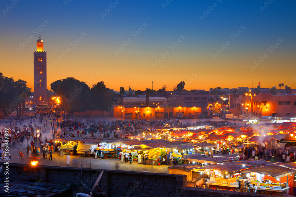 Famous Jemaa el Fna square crowded at dusk. Koutoubia minaret as background. Marrakesh, Morocco