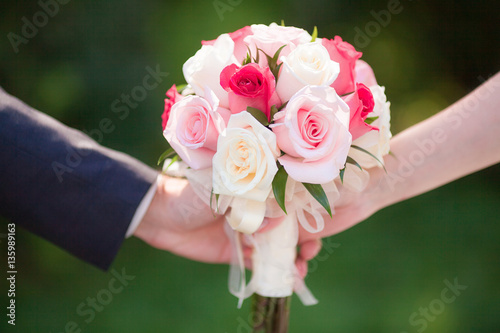 Beautiful pink wedding bouquet in hands of bride and groom