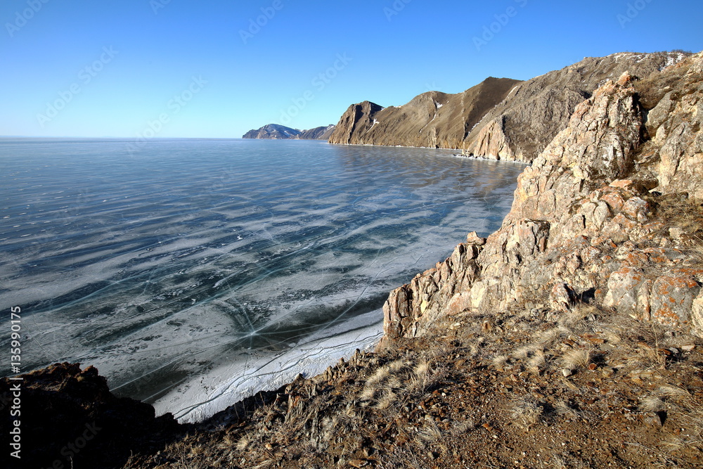 Rocky shore of lake Baikal in winter Rocky headland on the Western coast of lake Baikal sticks in ice-covered water body, forming a cozy Bay with a pebble beach 