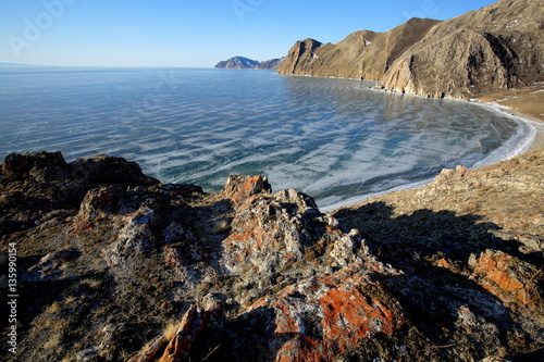 Rocky shore of lake Baikal in winter Rocky headland on the Western coast of lake Baikal sticks in ice-covered water body, forming a cozy Bay with a pebble beach 