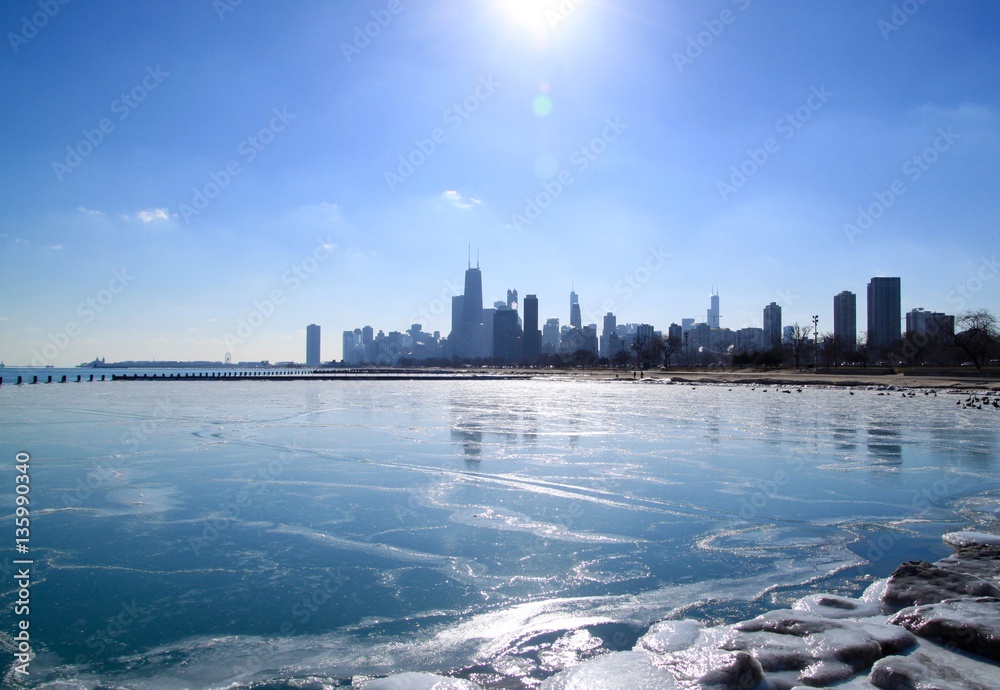 Obraz premium Słońce świeci jasno nad panoramą Chicago, która odbija się na zamarzniętym jeziorze Michigan