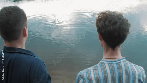 Two men stand shore looking at coming out water scooba diver on a summer day photo