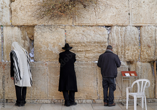 JERUSALEM - JANUARY 2017:  Jews worship at the stones of  the Western Wall, where the crevices are stuffed with notes of supplication, as seen in Jerusalem circa 2017.
