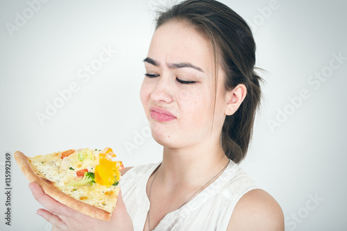 unhappy woman with piece of pizza on white background