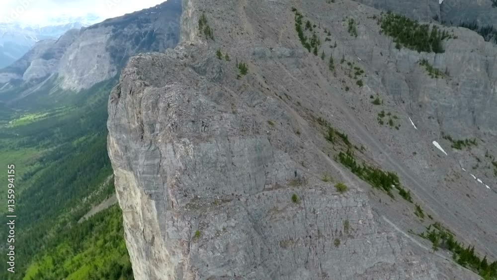 Aerial: Orbit around vertical mountain face with hikers climbing Aerial: Orbit around vertical mountain face with hikers climbing