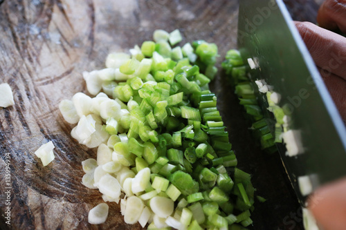 Handful of finely chopped green onions on striped wooden board