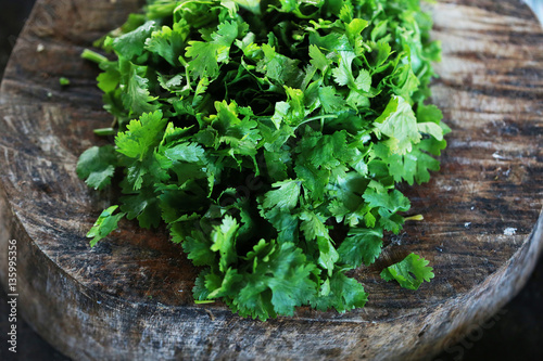 Fresh green cilantro, coriander leaves  with slice on wooden surface