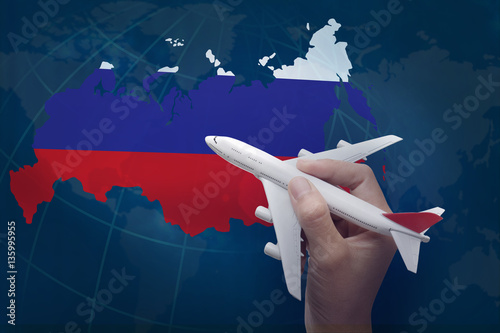 hand holding airplane with map of Russia.