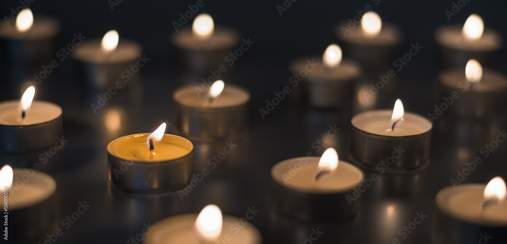 Flame of many candles burning on the background brown color Flame of many candles burning on the background brown color