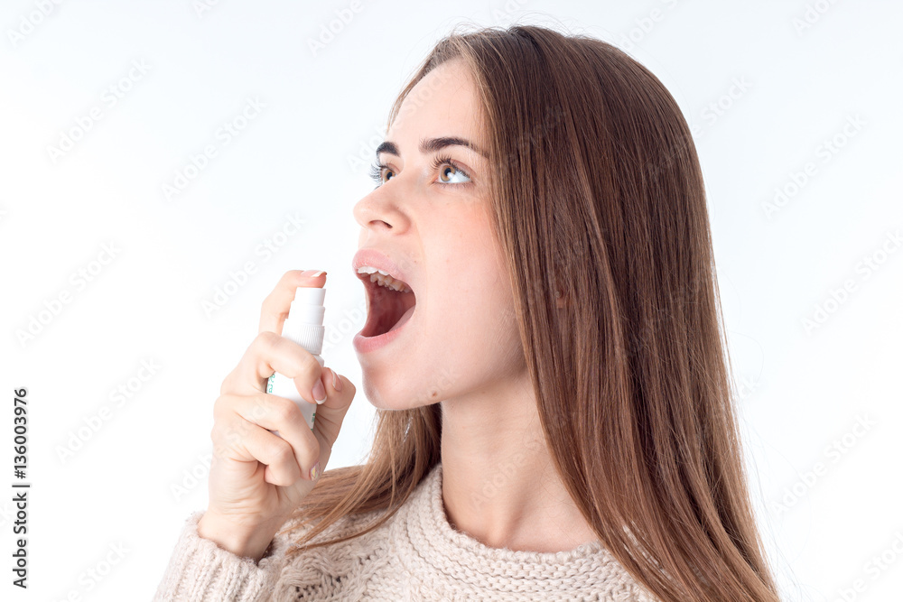 young girl turned her head and squirting a throat medicine young girl turned her head and squirting a throat medicine