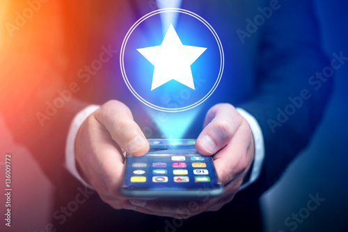 Businessman hand holding mobile phone with favorite star icon photo