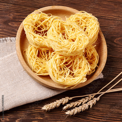 Raw pasta fettuccine in a wooden bowl photo