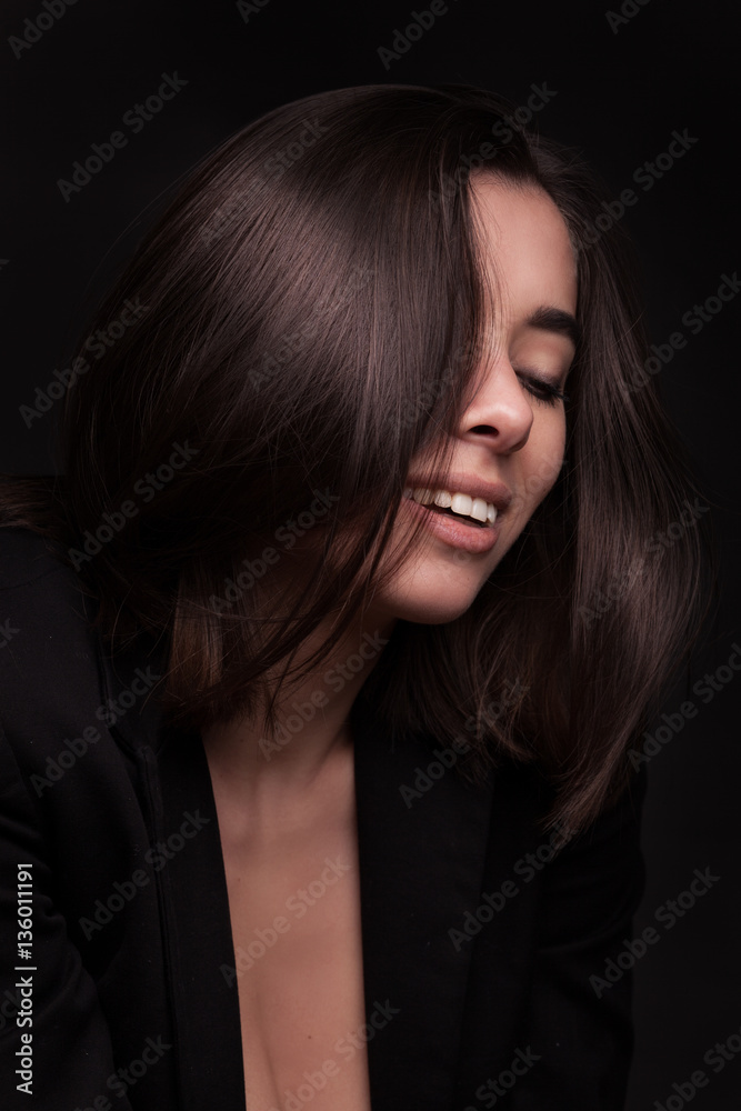 Portrait of a beautiful smiling woman with flying brown hair over black studio background Portrait of a beautiful smiling woman with flying brown hair over black studio background