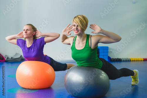 Two young sporty women doing gymnastic exercises or exercising in fitness class