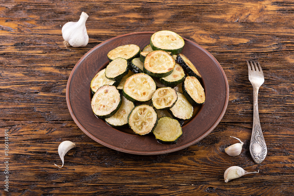 Fried zucchini in a clay plate on a wooden table Fried zucchini in a clay plate on a wooden table