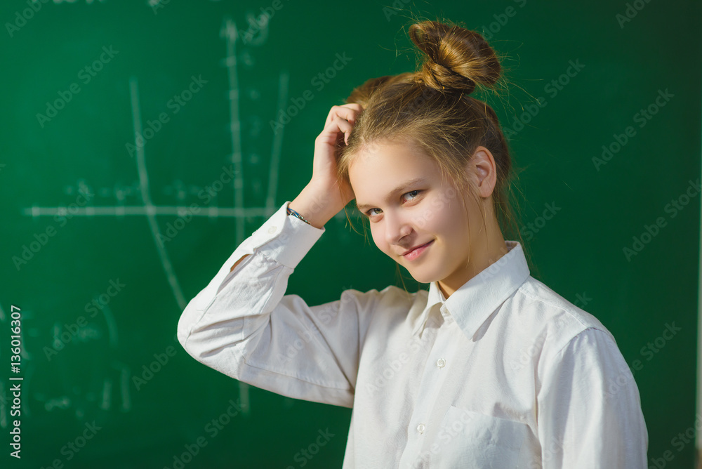 Girl thinking on blackboard background . Educational and school concept