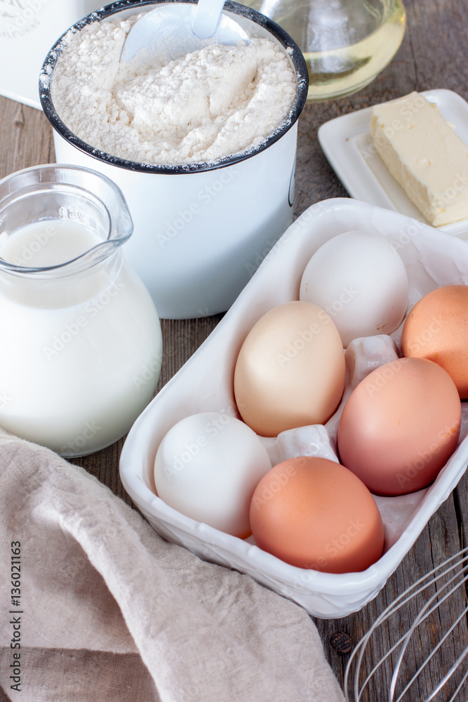 ingredients for making pancakes or cake - flour, egg, butter, milk on the old wooden background. ingredients for making pancakes or cake - flour, egg, butter, milk on the old wooden background.