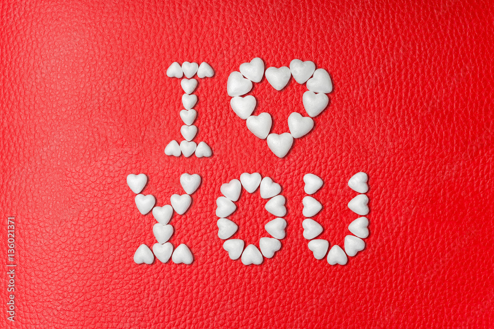 The inscription I LOVE YOU made from white hearts on red leather background