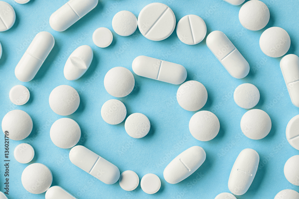white medicine pills on blue background white medicine pills on blue background