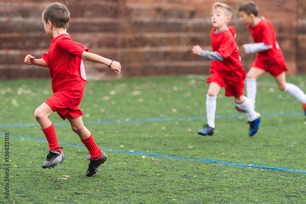 Obraz premium Boys kicking soccer ball at sports field