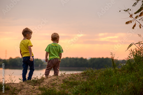 дети стоят на берегу на закате