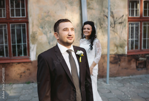 Groom in the black suit and his bride behind