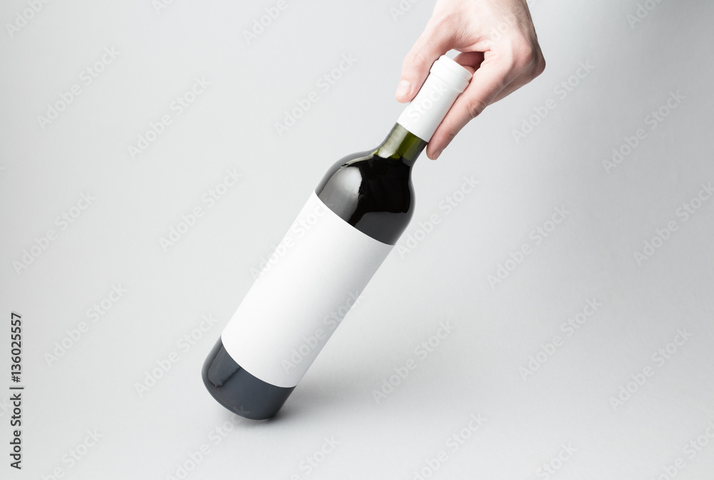 Hand is holding wine bottle on gray background Hand is holding wine bottle on gray background