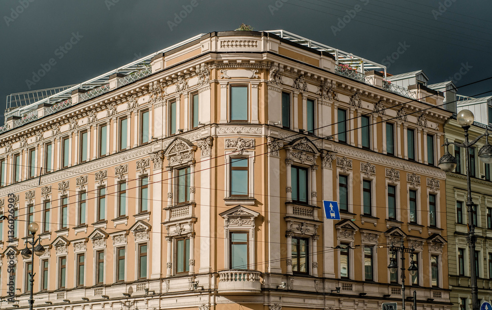 A picture of a vintage old classic typical european urban house facade building with windows and a storm sky above