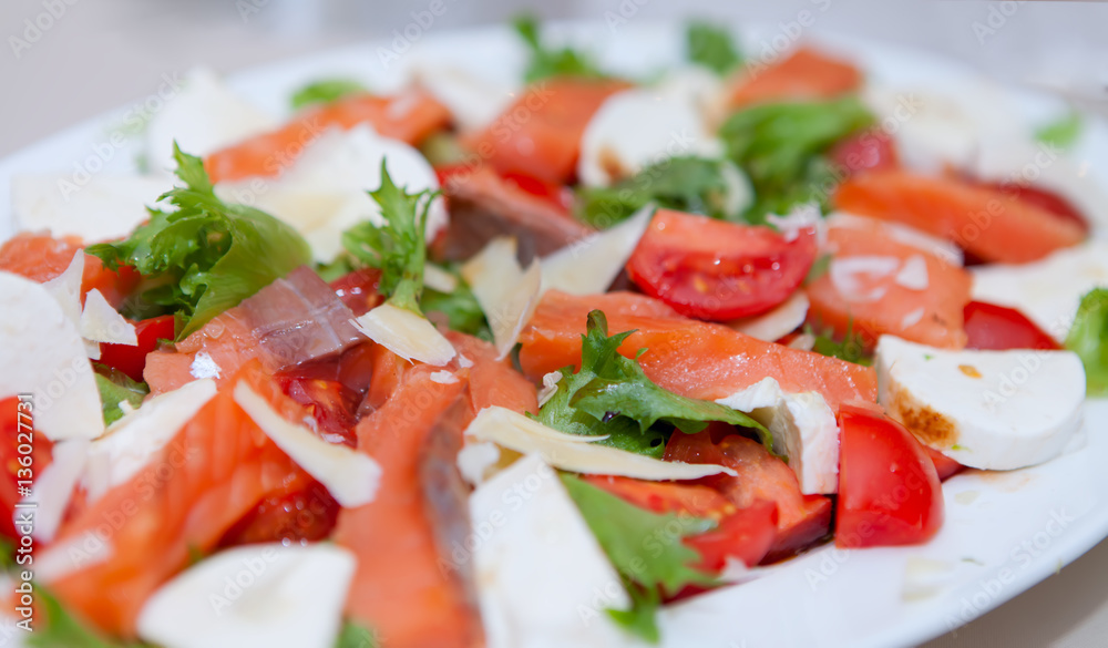 Salad tomatoes, cheeses, seafood in white dish on the holiday table Salad tomatoes, cheeses, seafood in white dish on the holiday table