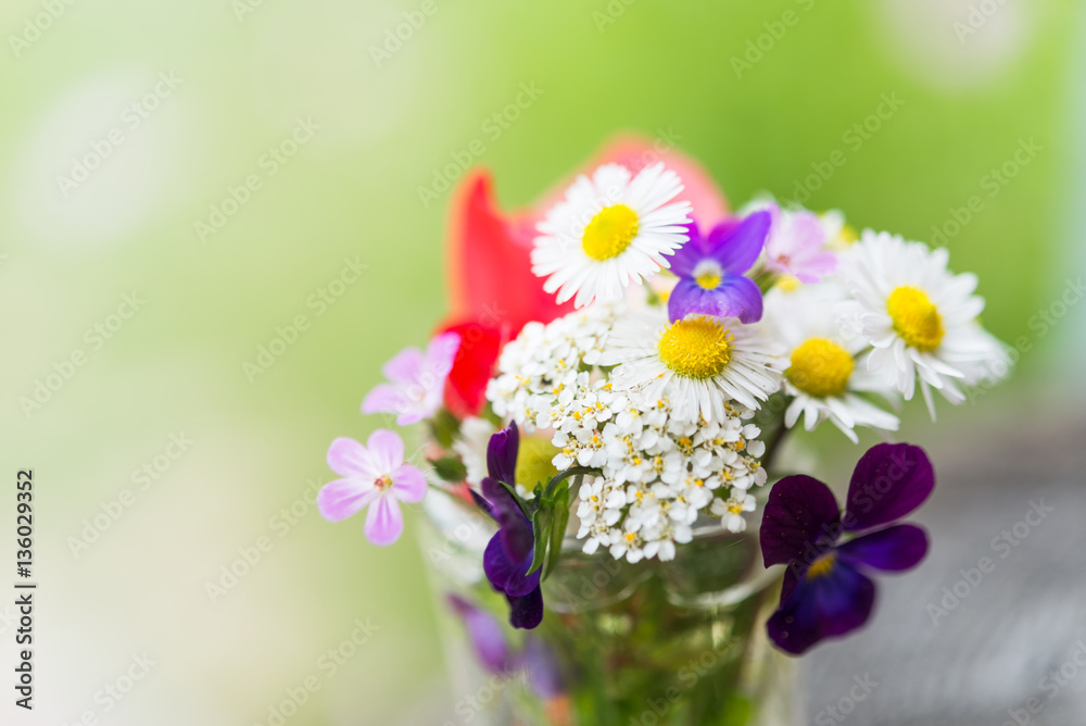 Bouquet of colourful garden flowers in a glass on old tree trunk Bouquet of colourful garden flowers in a glass on old tree trunk